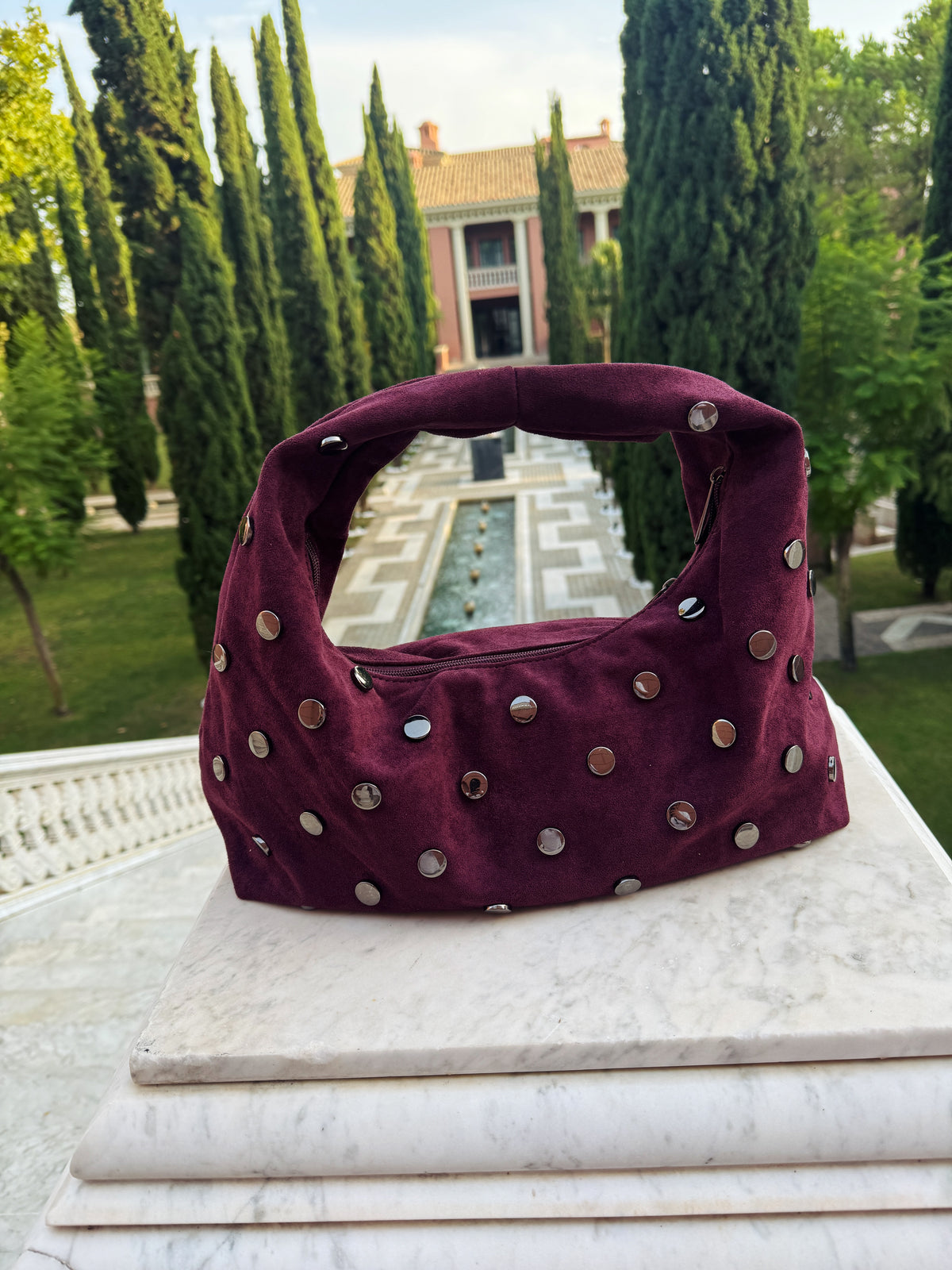Aubergine Élise Bag – dameshandtas met zilveren studs van Gabianna Fashion, gefotografeerd in een elegante tuinomgeving